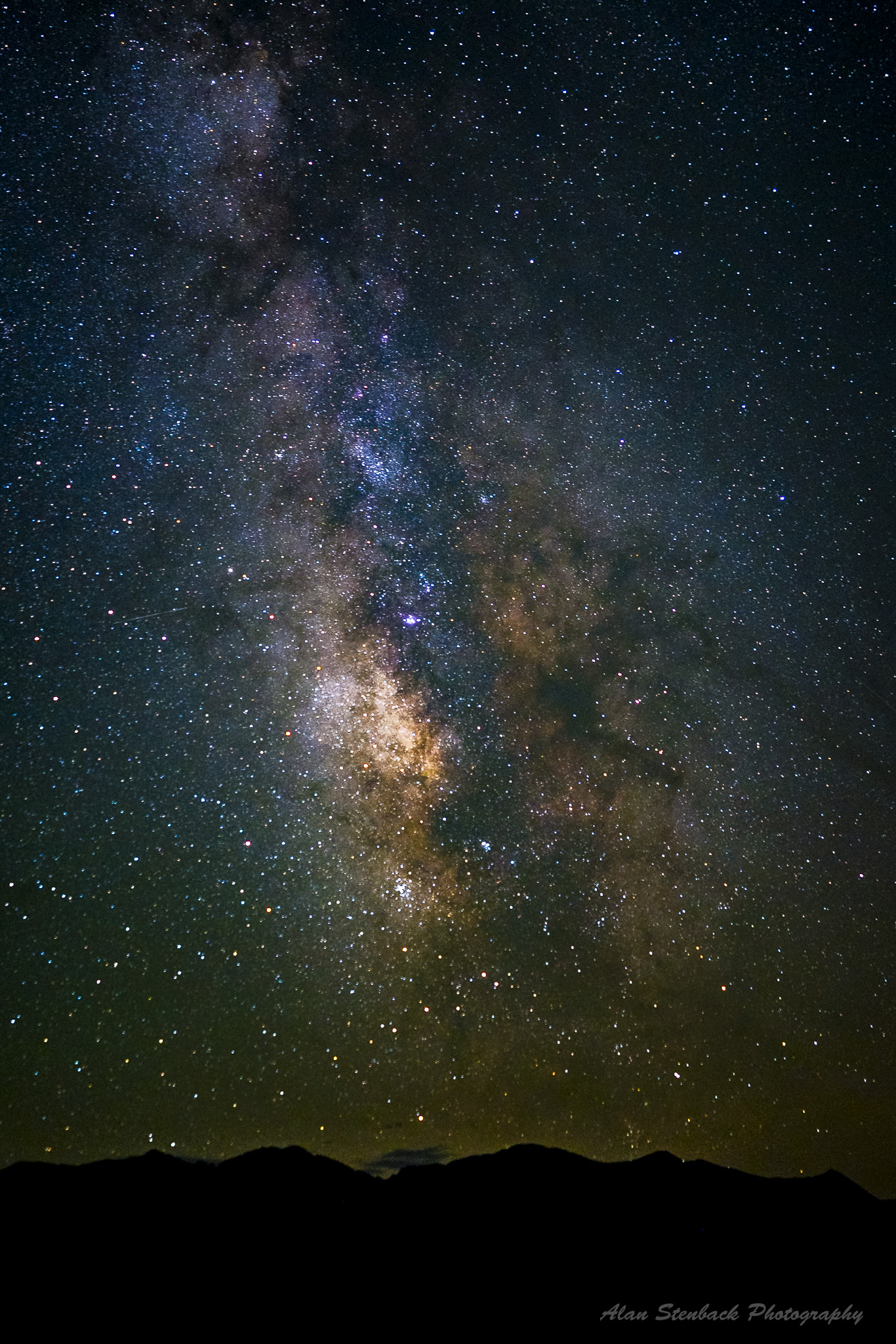 Milky Way galaxy over mountain silhouette, vibrant night sky filled with stars and cosmic dust.