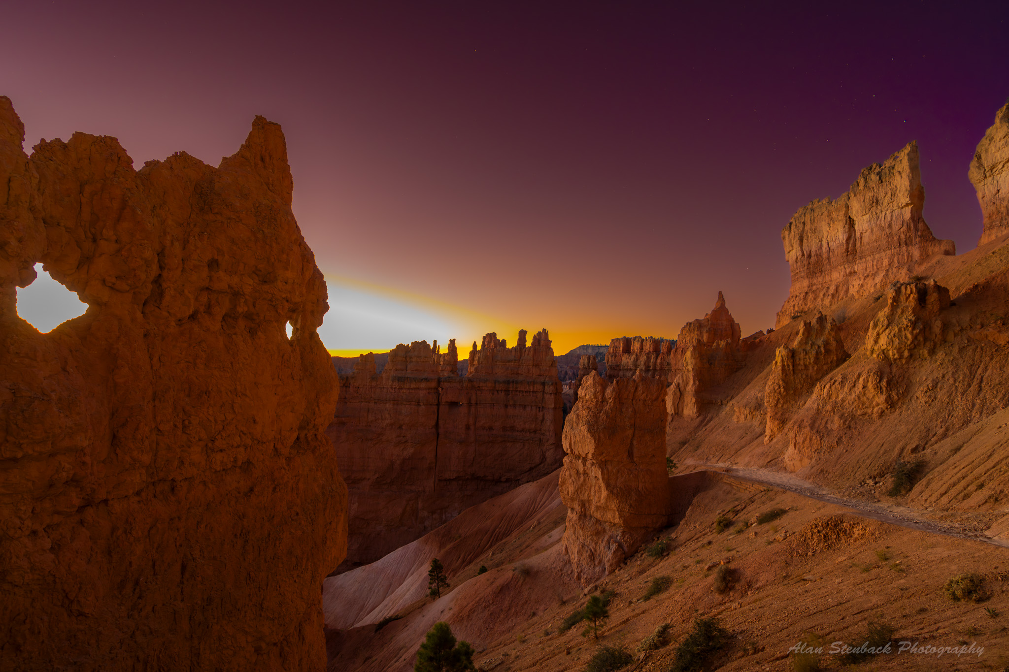 Bryce Canyon National Park at sunrise, showcasing striking hoodoos and rock formations under a purple and orange sky.