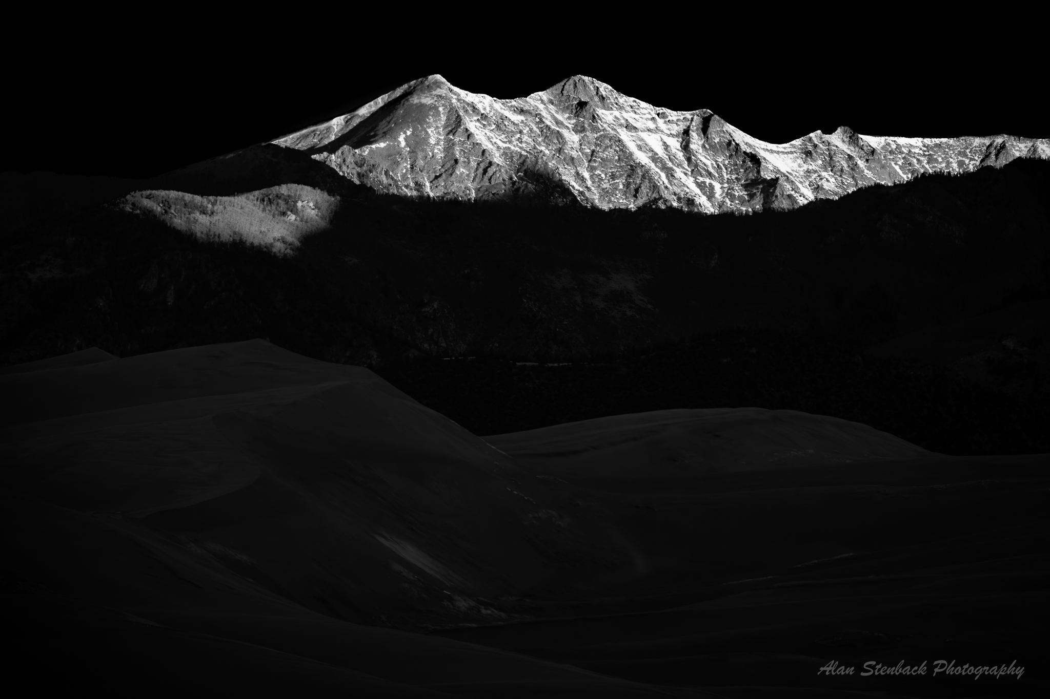Snow-capped mountain peak illuminated against dark background, capturing dramatic contrast and serene natural beauty.