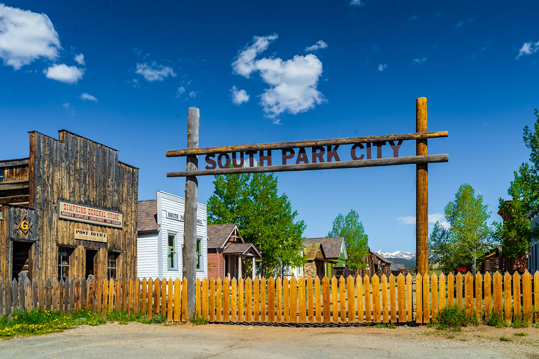 South Park City entrance with rustic wooden signage and historic buildings under a clear blue sky, representing a preserved old Western town.