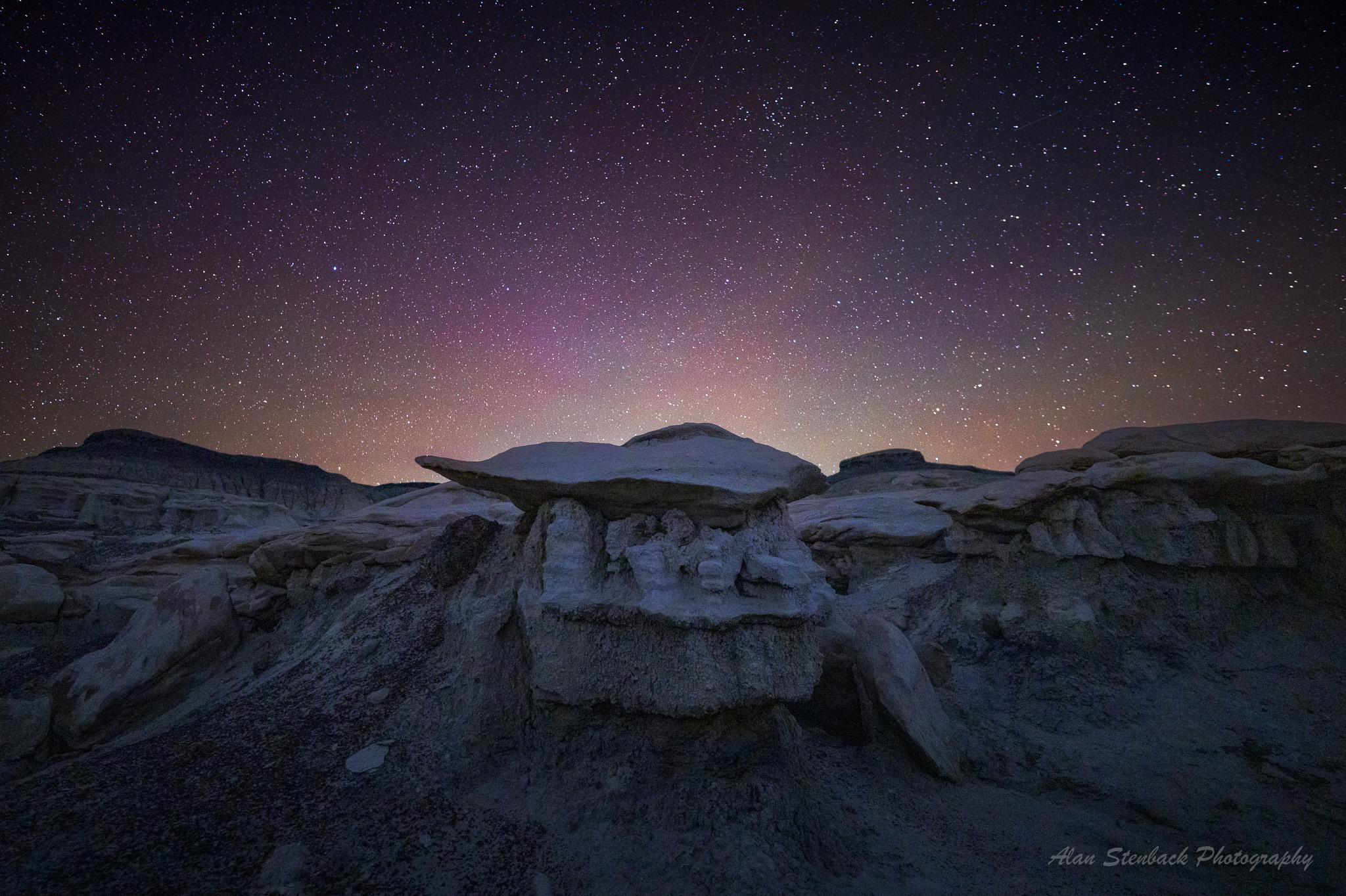 Starry night sky over desert rock formations, creating a serene and mystical landscape.