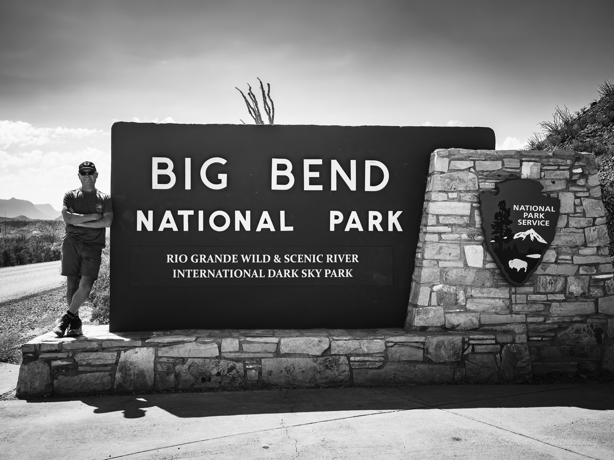 Big Bend National Park entrance sign with person standing beside it, highlighting Rio Grande Wild & Scenic River and International Dark Sky Park designation.